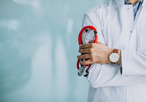Young handsome physician in a medical robe with stethoscope