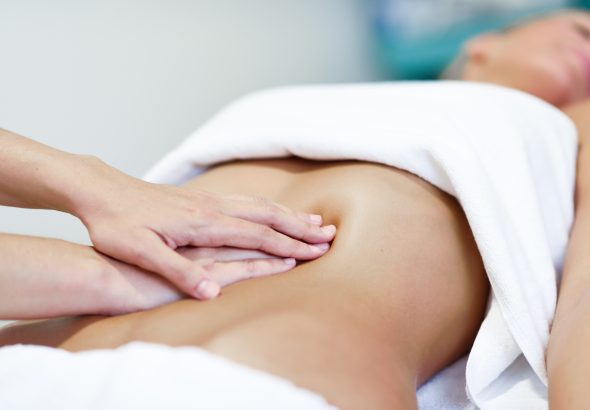Hands massaging female abdomen.Therapist applying pressure on be